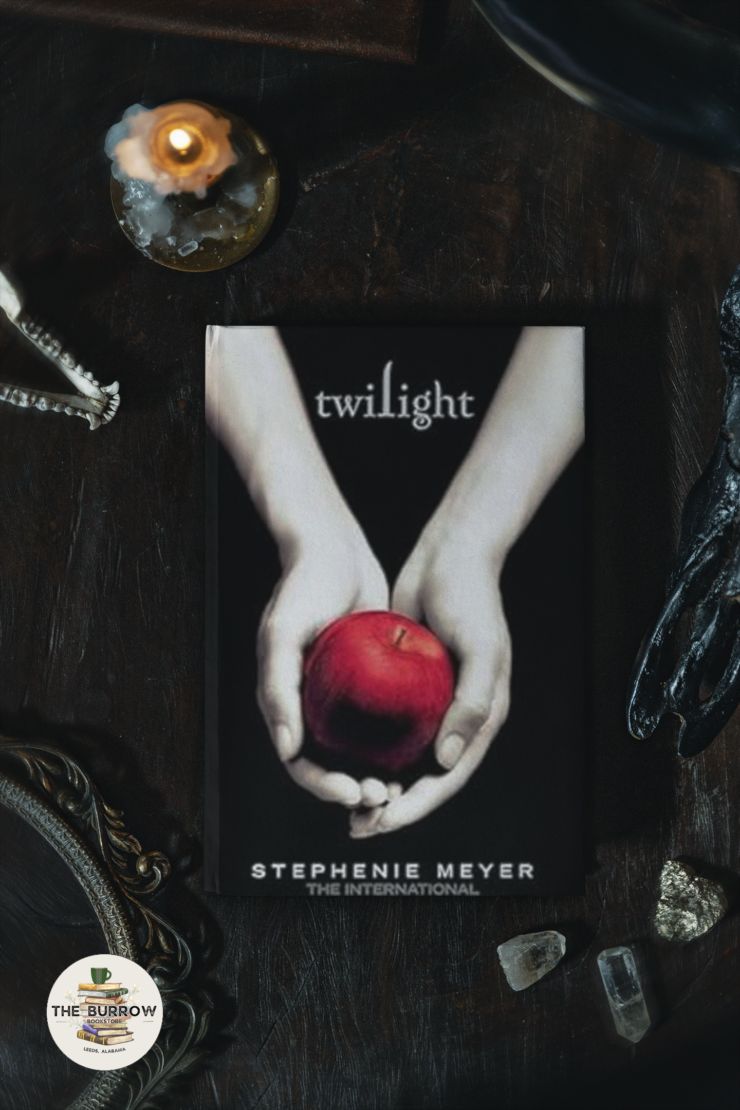 The image displays the hardback version of Stephenie Meyer's novel 'Twilight'. The cover shows a stylized image of a woman's hands holding an apple, with the title 'Twilight' and the author's name, 'Stephenie Meyer', printed above.