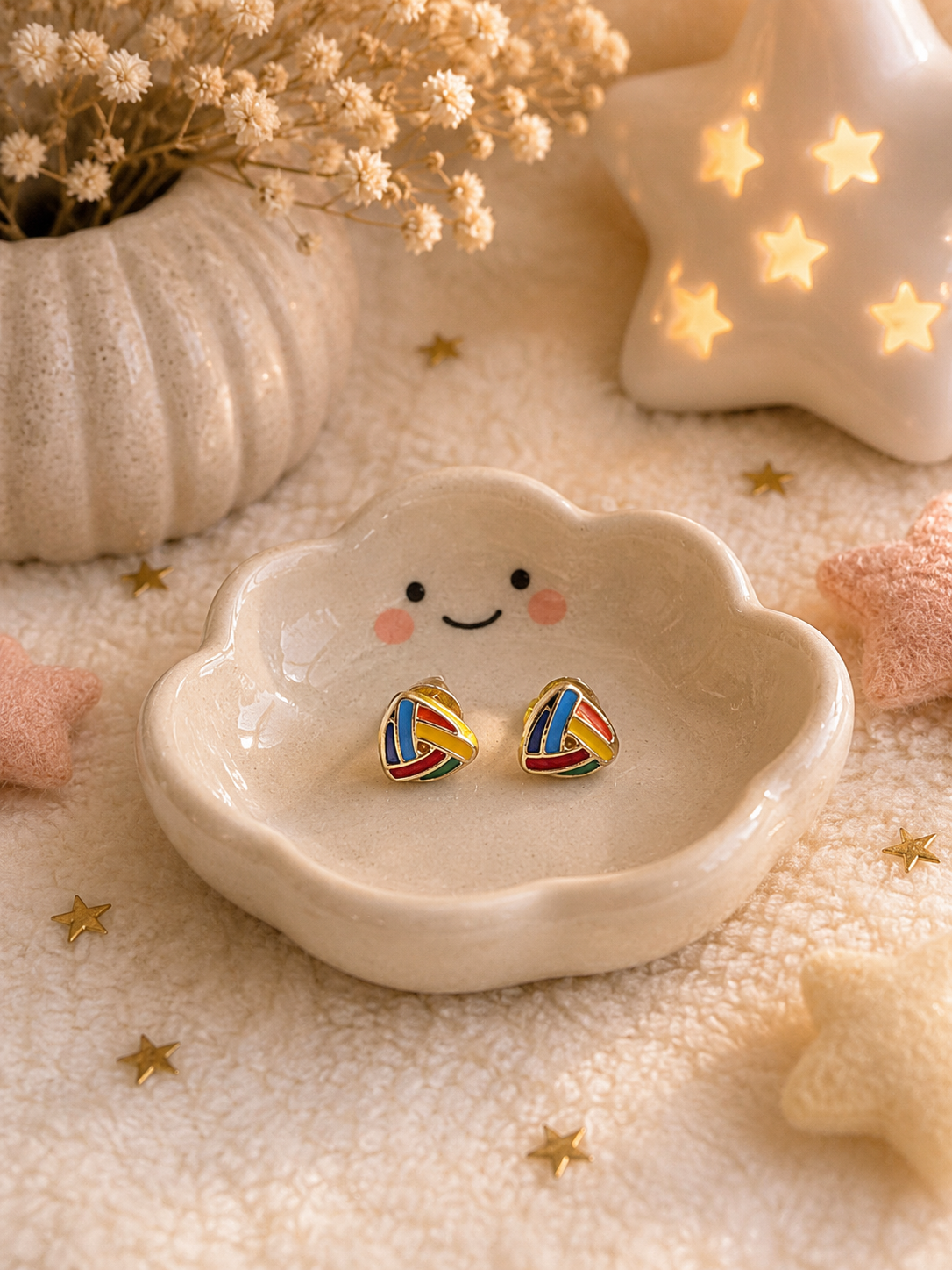 Minimalist rainbow knot stud earrings displayed in smiling ceramic dish with cozy decor