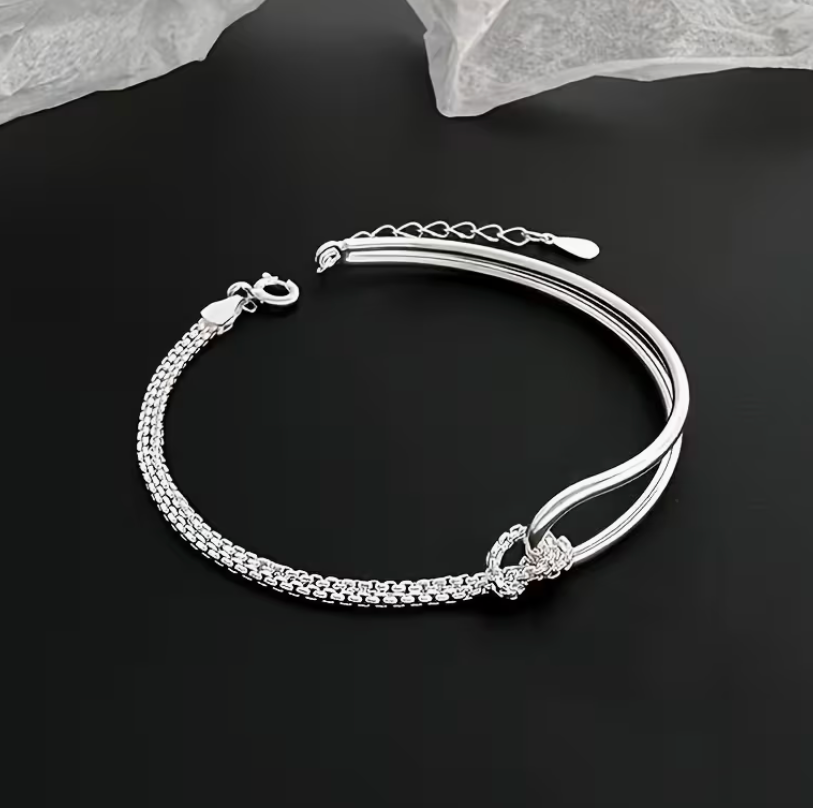 Elegant silver-tone layered bracelet featuring a decorative knot accent and adjustable fit.
