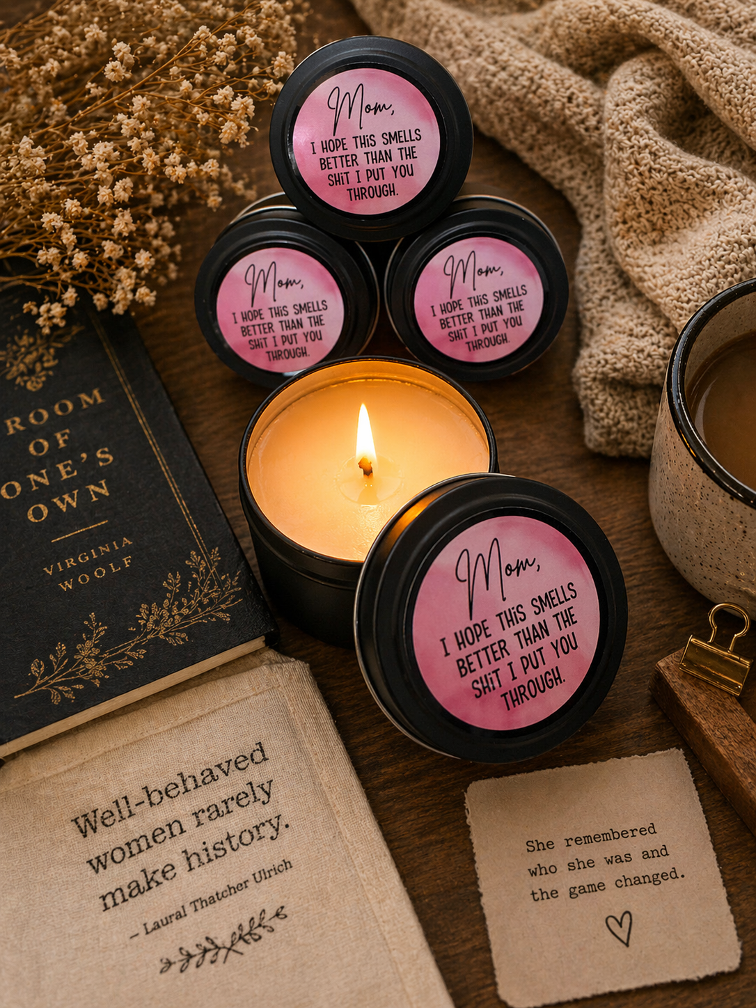 Candle with 'Mom' tins and a book on a wooden surface