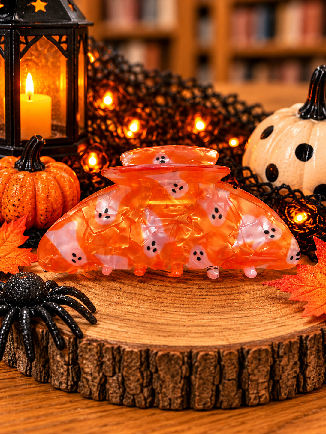 Orange Halloween ghost hair claw clip featuring white ghost patterns, translucent orange marbled finish, and interlocking teeth.