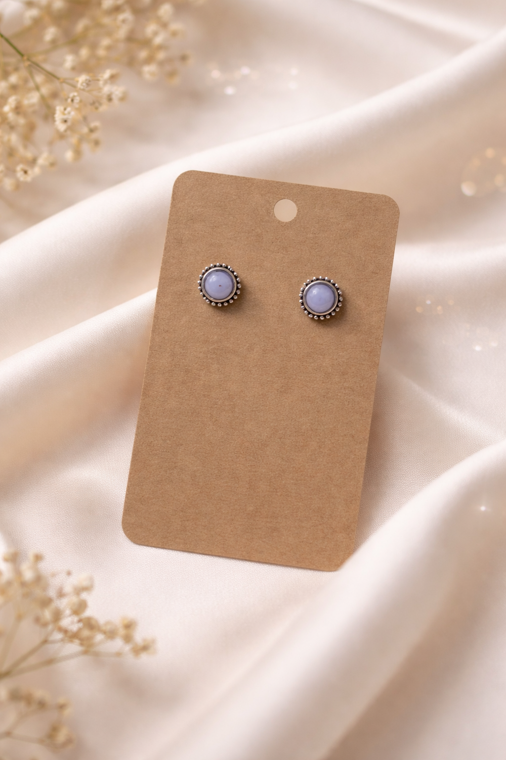 Pearl stud earrings with silver tone setting displayed on a neutral card with a soft light background