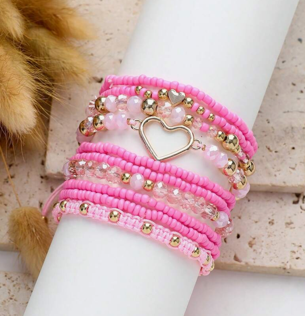 Pink beaded bracelet with heart charm on a white mannequin wrist against a neutral background