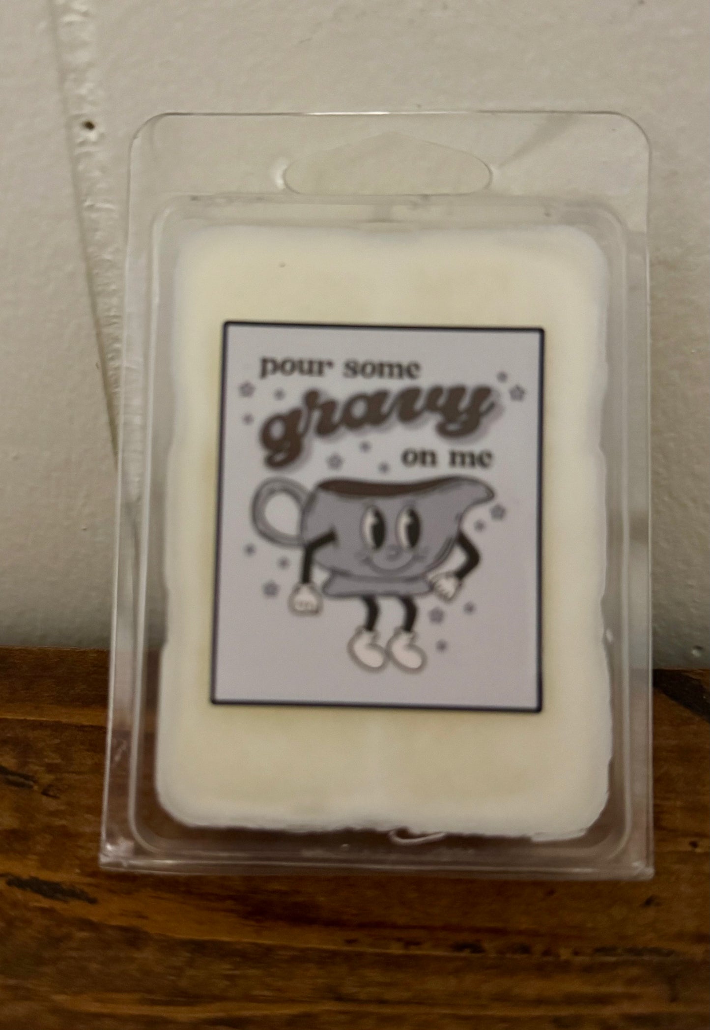 Wax melt with cartoon cup and text 'pour some gravy on me' in a clear packaging.