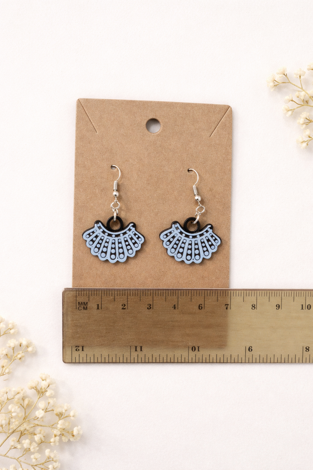 Ruth Bader Ginsburg dissent collar earrings on display card with ruler showing size for scale.