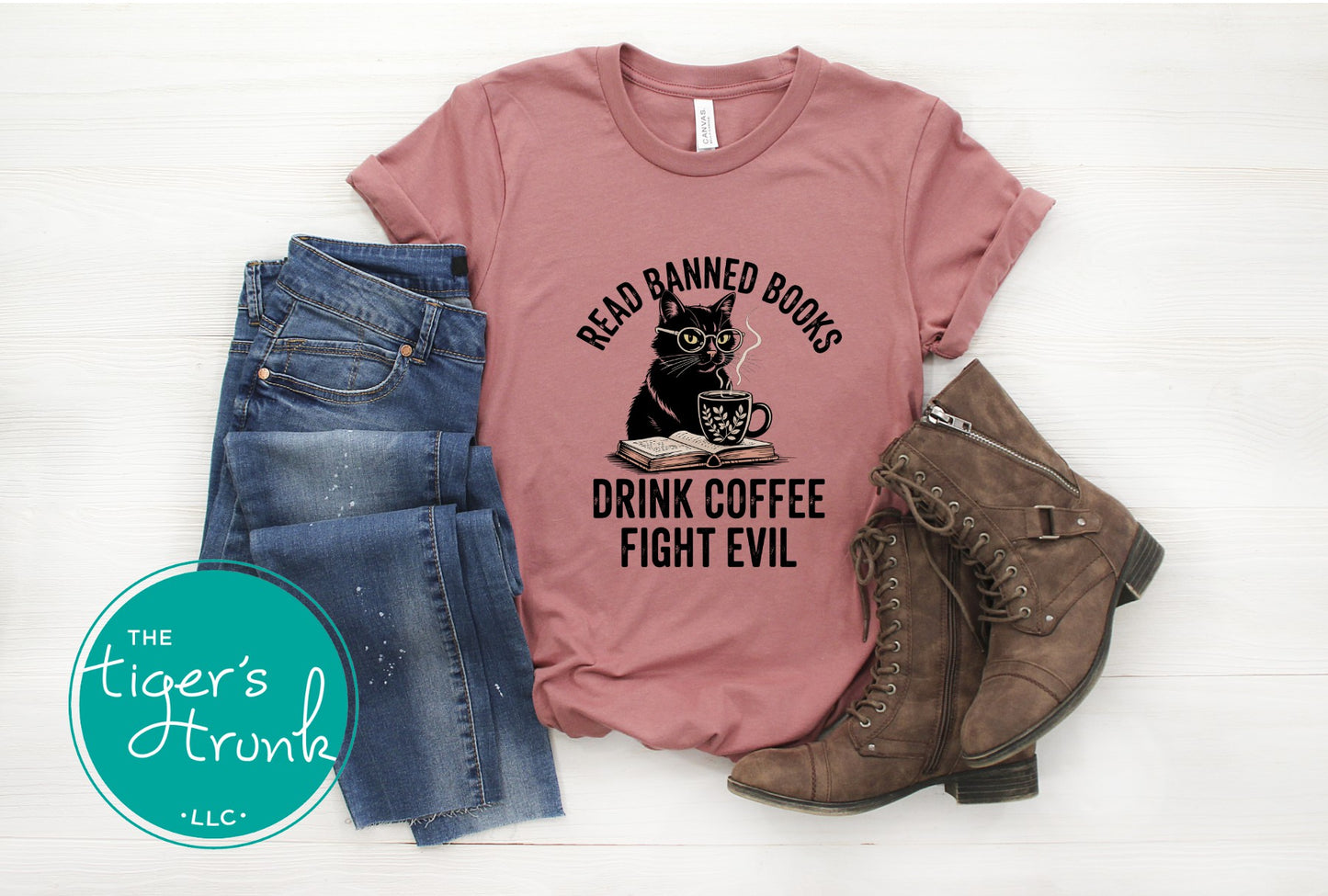 Pink t-shirt with a cat graphic and text, paired with jeans and boots on a white background.