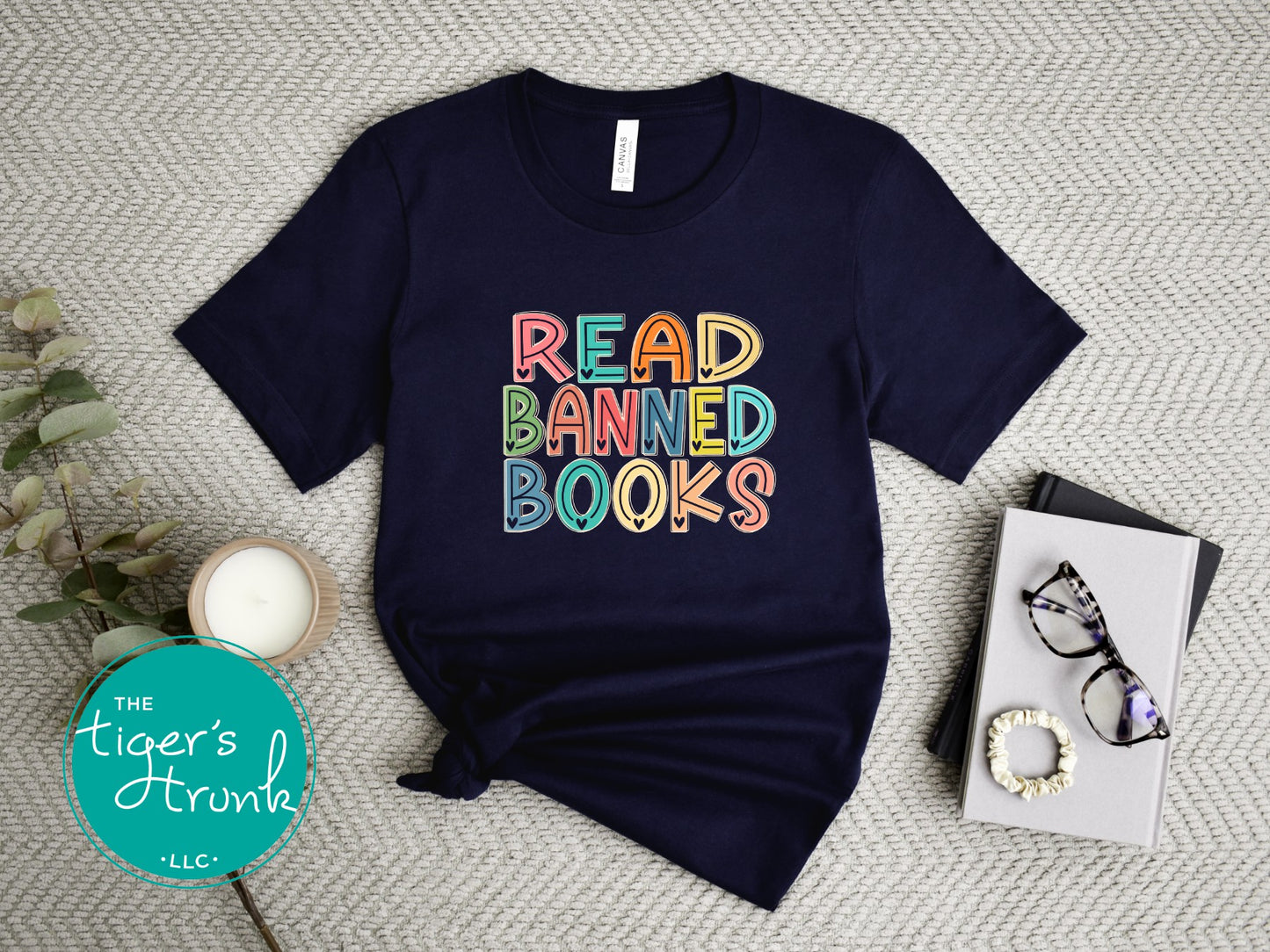 Navy blue t-shirt with 'Read Banned Books' text on a textured surface with decor items.
