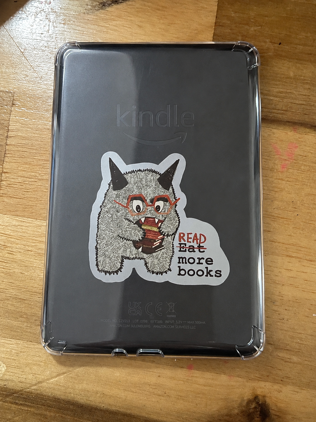 Cute Book Monster character vinyl sticker holding books with the phrase "Read More Books" displayed on the back of a Kindle.