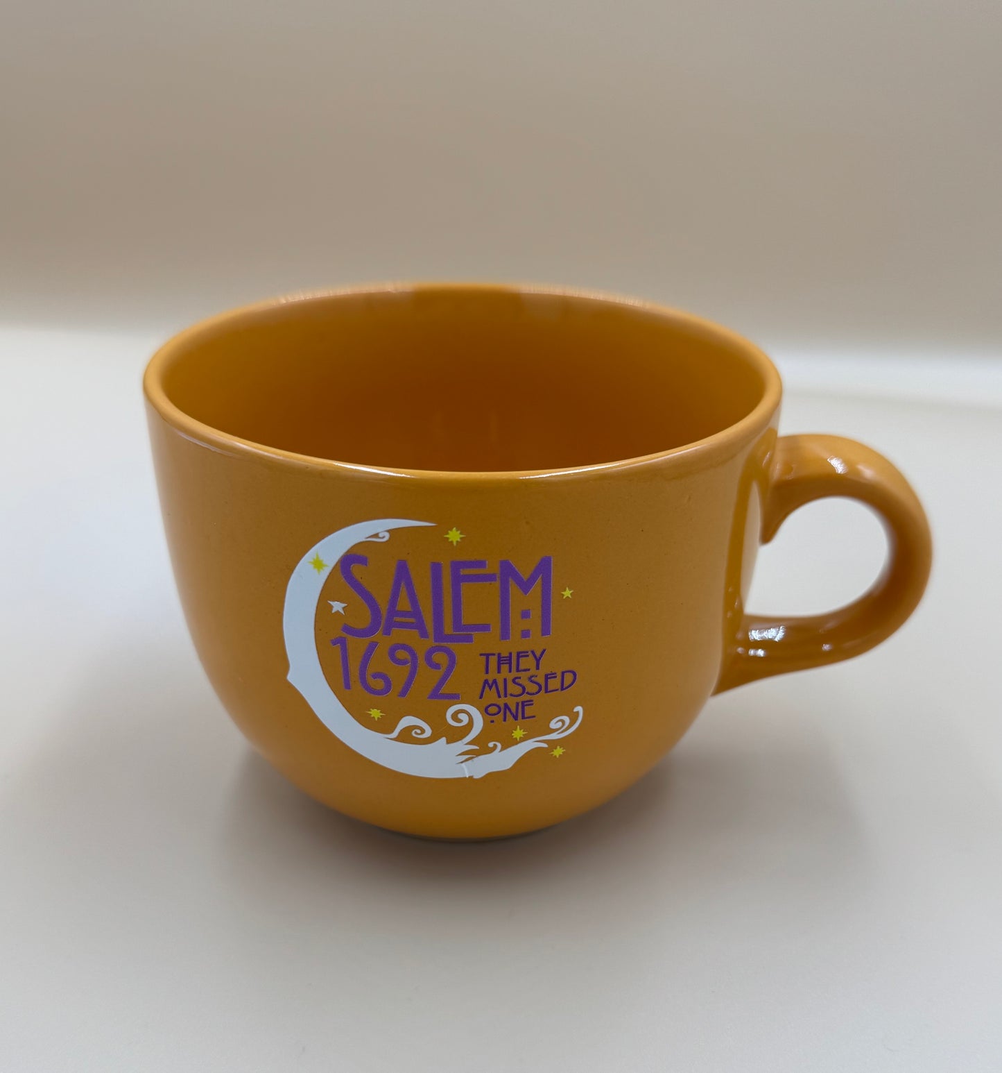Brown mug with 'Salem 1692 They Missed One' text on a white background
