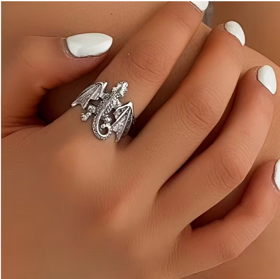 Silver-toned dragon ring worn on hand, featuring a detailed winged dragon design with curled tail and textured wings