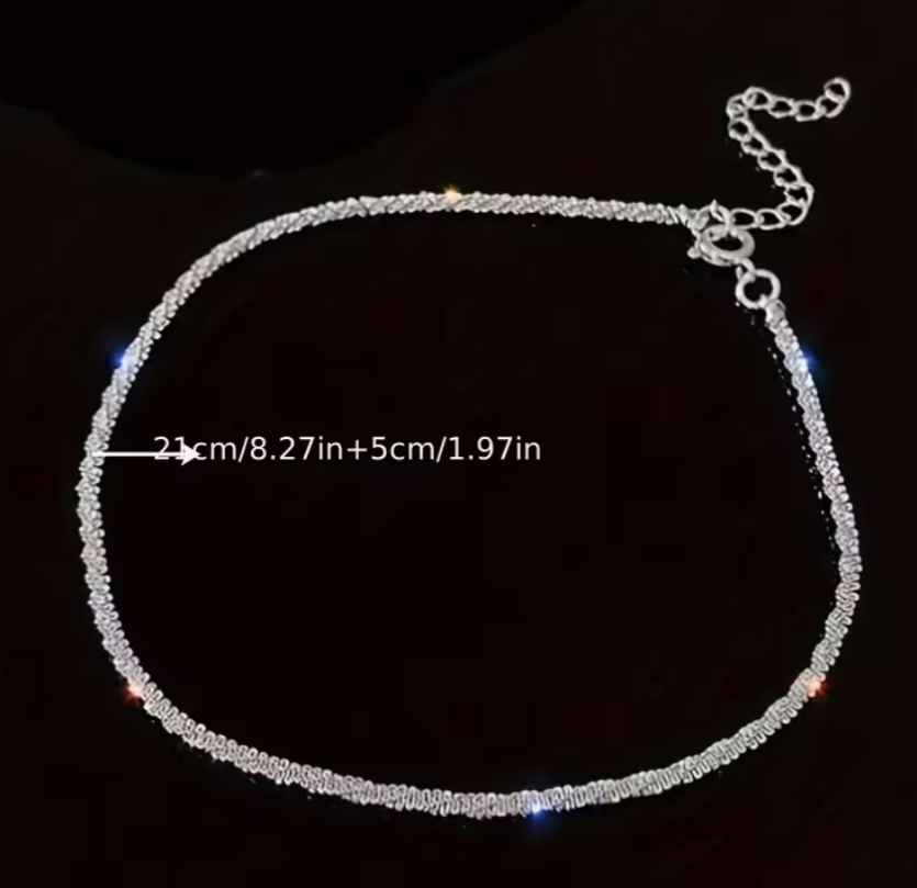 Silver tone adjustable anklet chain with extender clasp shown flat on dark background, delicate ankle bracelet measuring approximately 8.27 inches plus extender