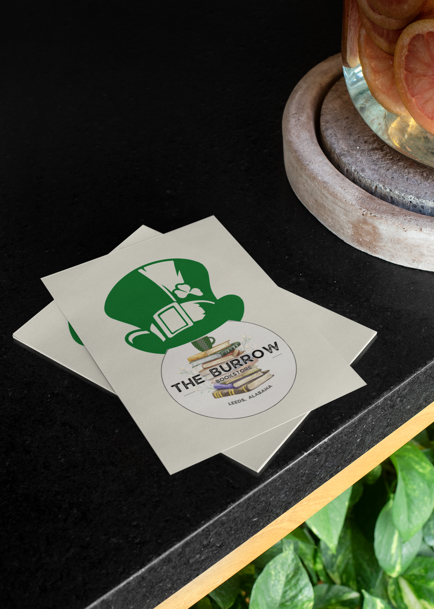 A festive St. Patrick’s Day postcard featuring The Burrow Bookstore logo with a leprechaun hat on top, perfect for book lovers and holiday celebrations.
