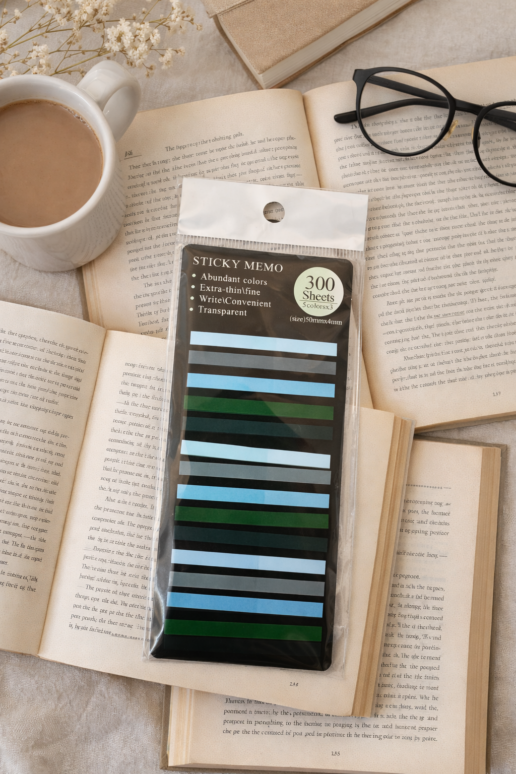 Pack of transparent sticky memo page flags labeled Sticky Memo with 300 sheets displayed on open books beside a coffee mug and reading glasses in a cozy flat lay.