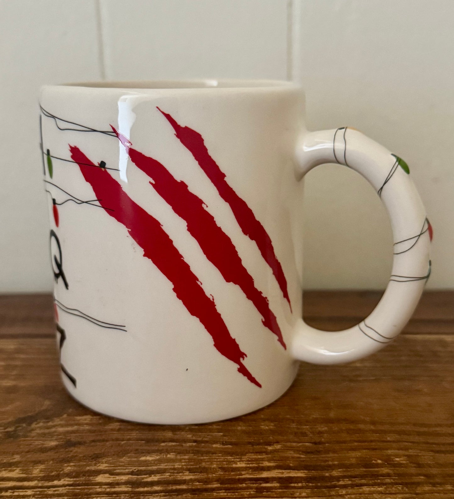 White mug with red claw marks and a handle on a wooden surface
