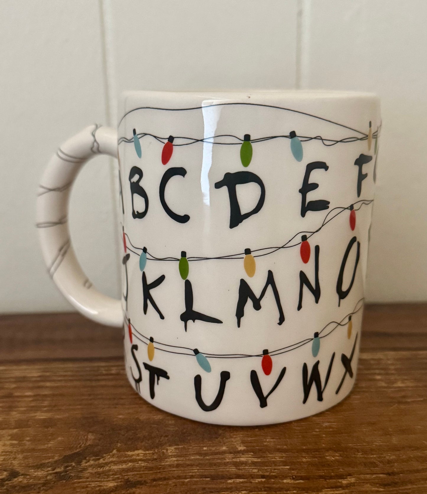 Mug with lettering and string lights design on a wooden surface