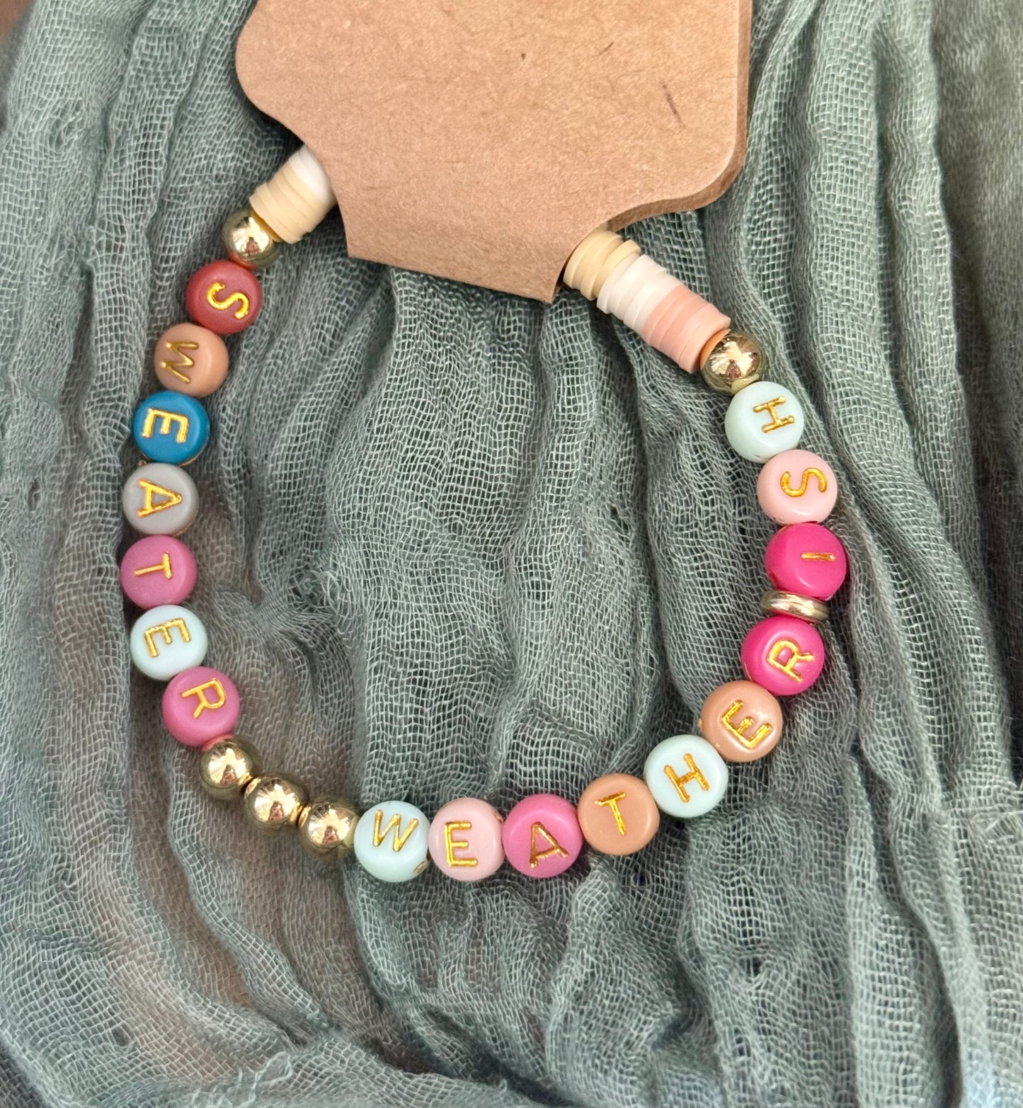Colorful beaded bracelet with letter beads on a gray fabric background