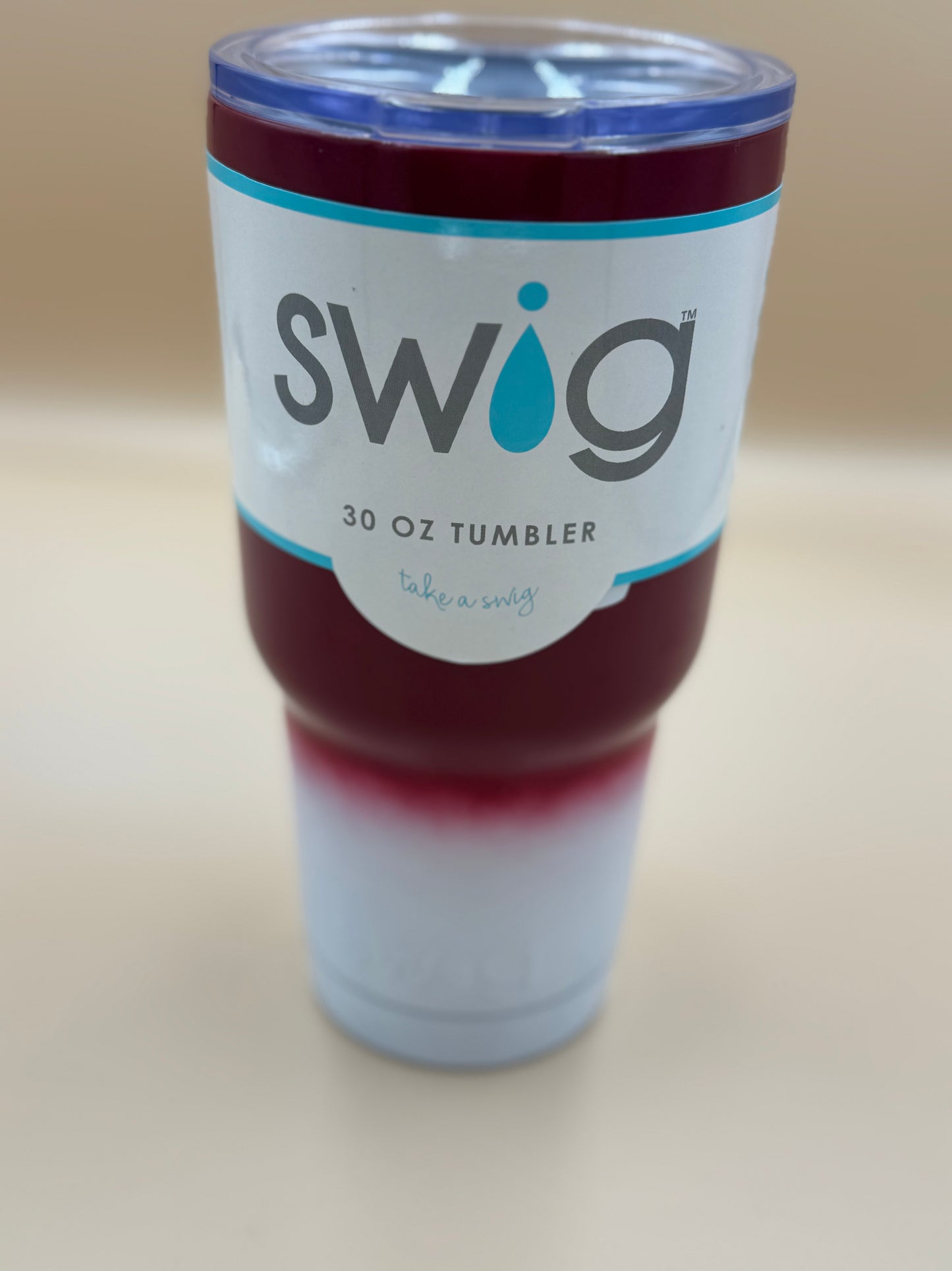 Swig tumbler with a red interior on a beige background