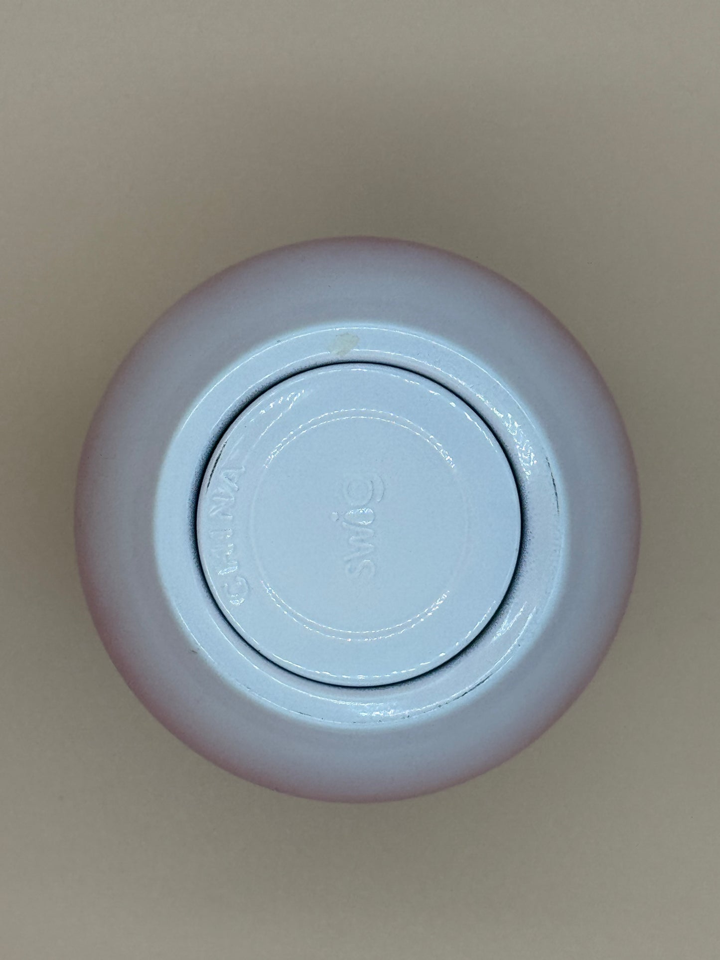 Top view of a light purple container with a circular lid on a beige background