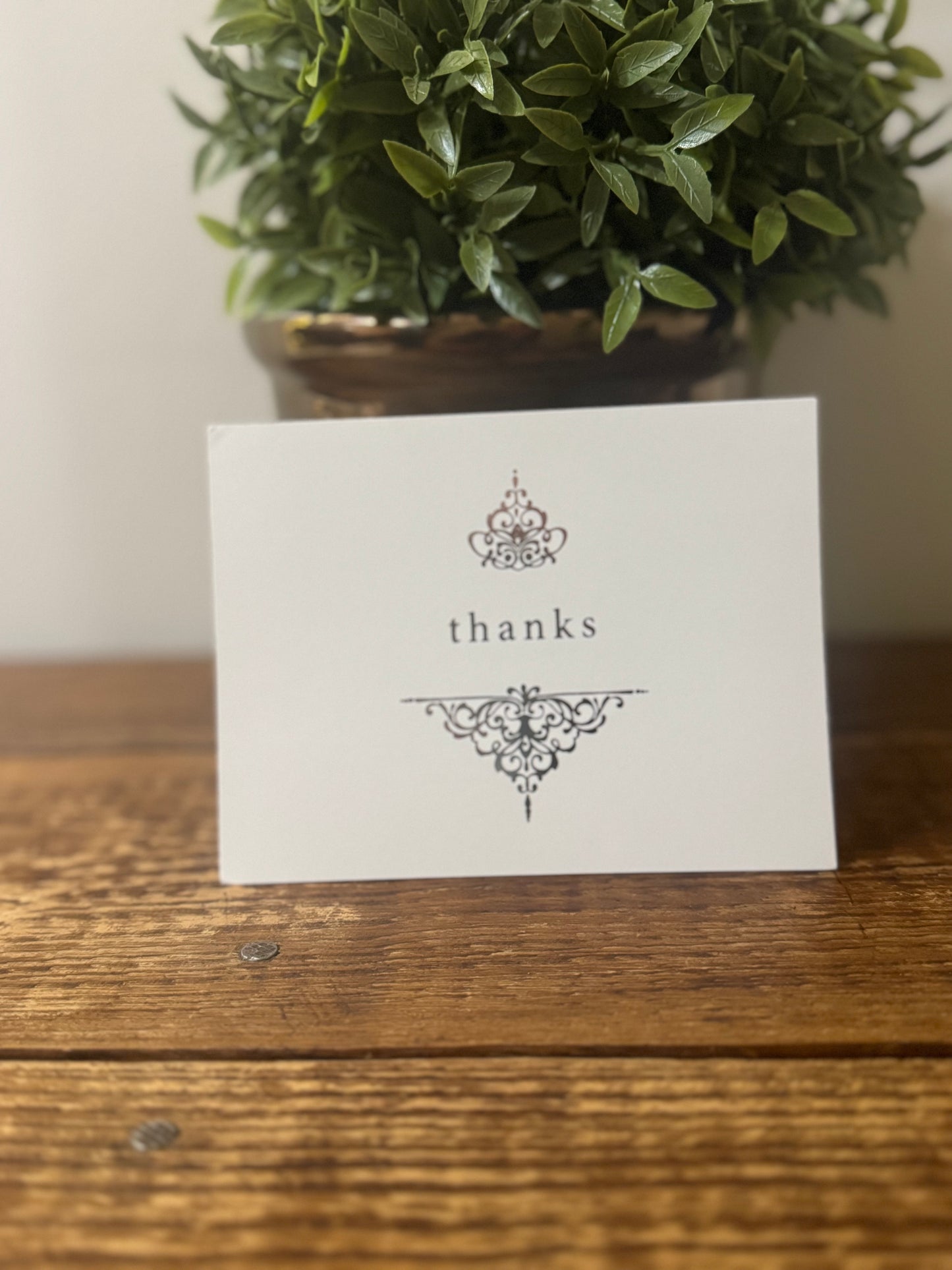 A sophisticated white thank-you card featuring silver font and delicate designs, perfect for any occasion.