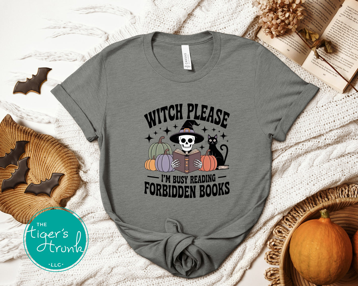 Gray t-shirt with Halloween-themed design on a textured surface with pumpkins and bats.