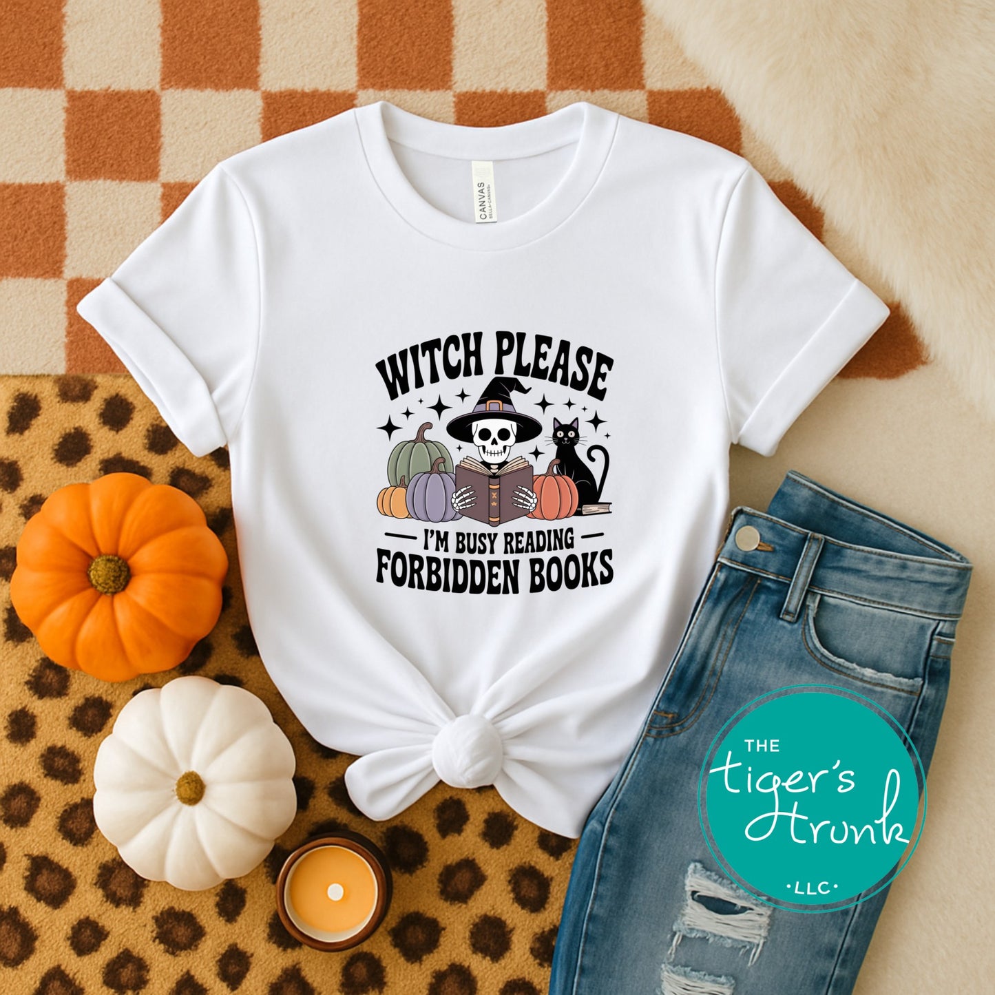 White t-shirt with Halloween-themed design on a checkered fabric background with pumpkins and jeans.