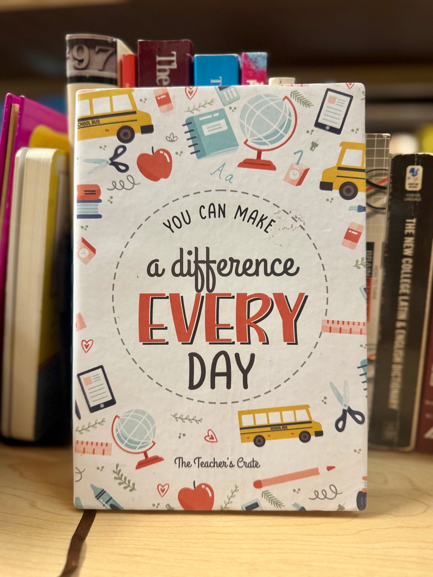 Notebook with 'You can make a difference every day' text and educational illustrations on a wooden surface.