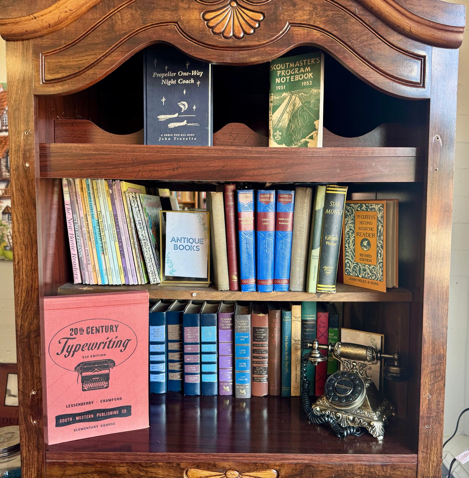A warm bookstore display featuring vintage books, collectable trinkets, antique-style décor, and old-fashioned keepsakes arranged on a rustic wooden table.