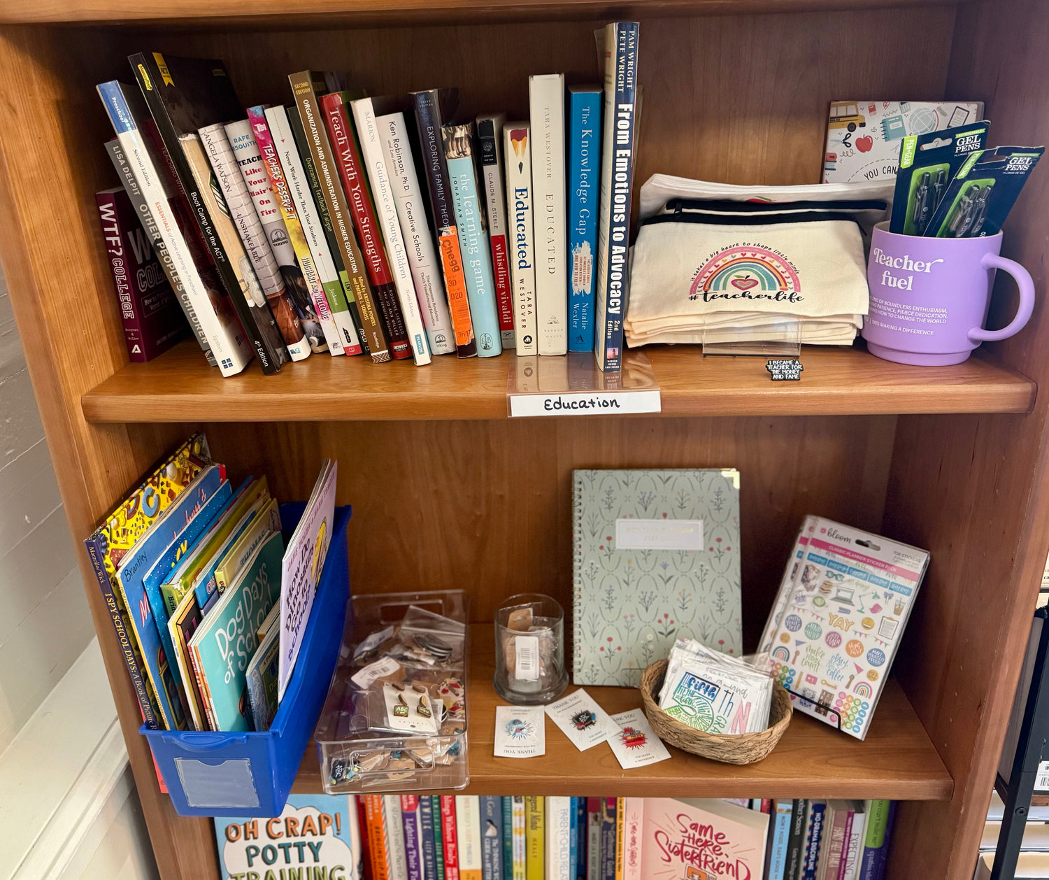 A tidy bookstore display featuring education-themed nonfiction books arranged beside notebooks, pencils, and a small chalkboard reading “Education,” with warm, welcoming lighting.