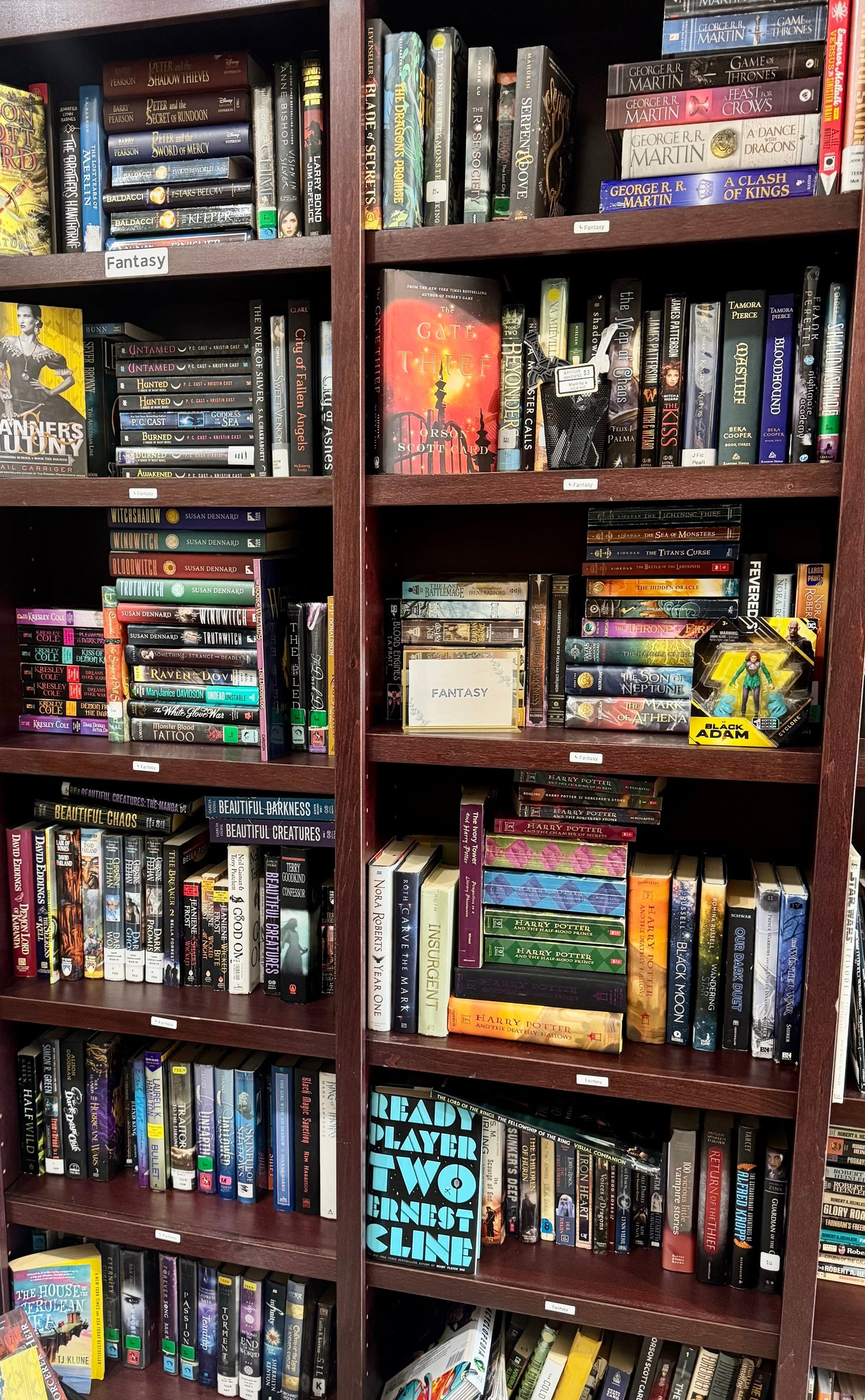 A moody bookstore display featuring fantasy novels with rich, colorful covers, surrounded by candles, crystals, and twinkling string lights for an enchanted atmosphere.