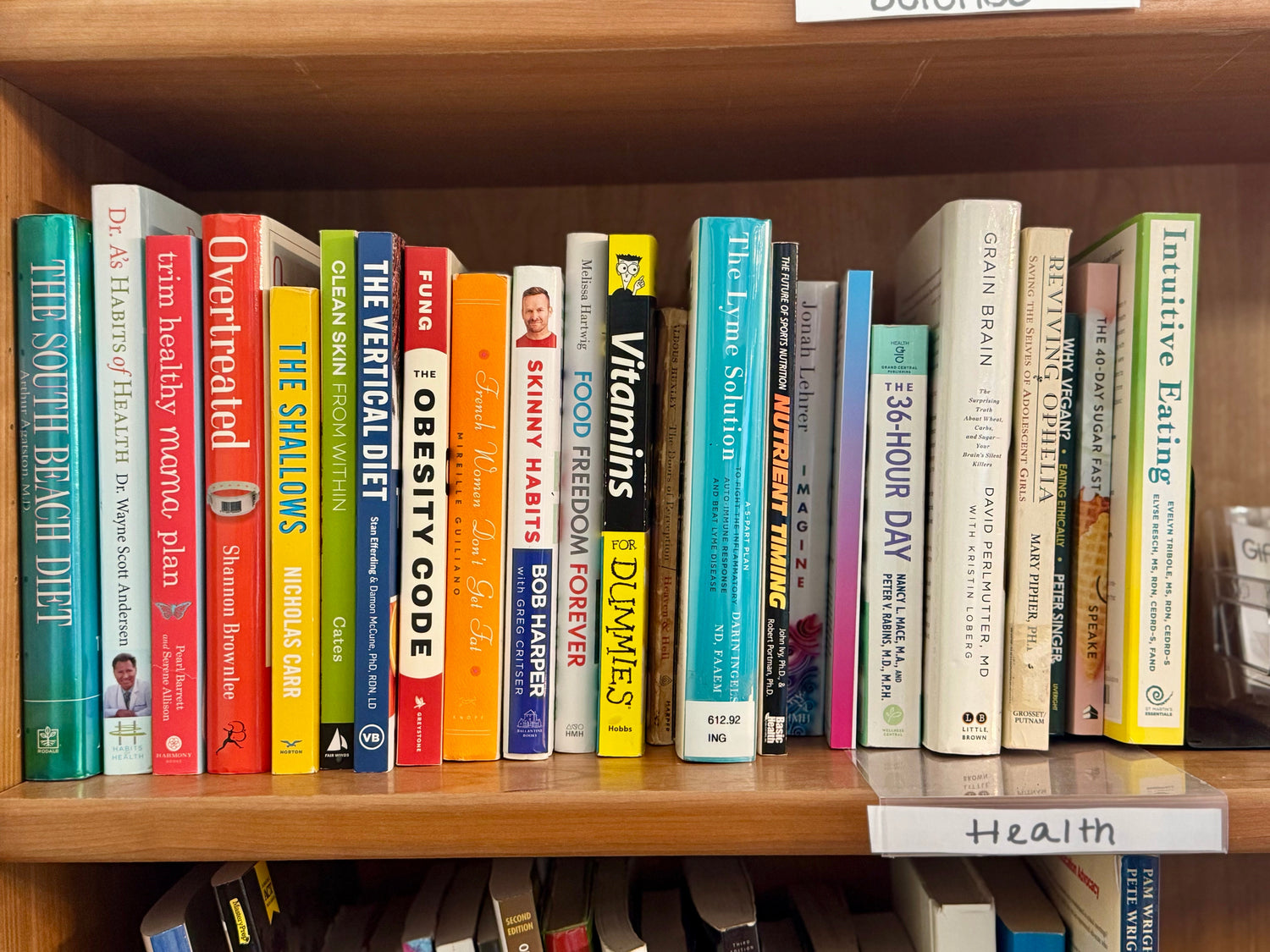 A calm bookstore display featuring health and wellness books arranged beside a small plant, a water bottle, and soft natural lighting for a peaceful, fresh look.