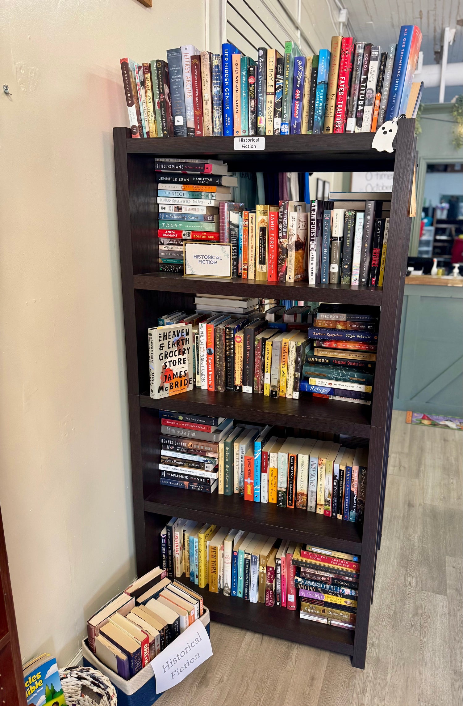 A softly lit bookstore table featuring historical fiction novels with vintage-inspired covers, antique props, and warm golden light for an old-world feel.