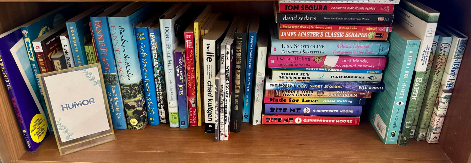A cheerful bookstore display featuring humor nonfiction books arranged beside fun, colorful décor with a small sign that says “Laugh a Little.”