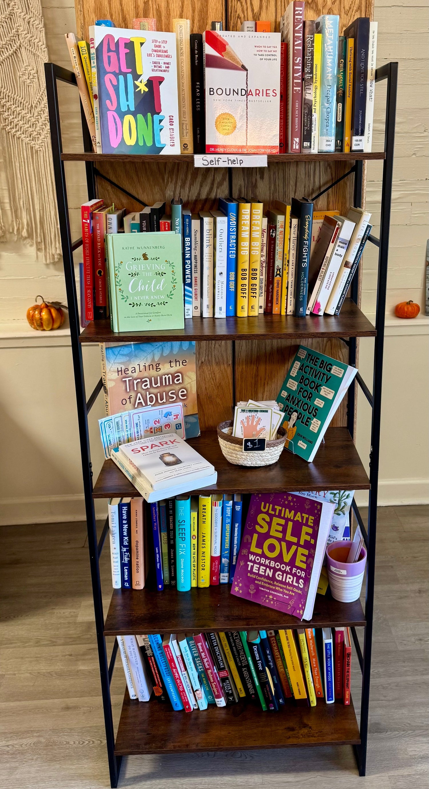 A calm bookstore display featuring self-help and wellness books arranged beside a cozy candle, a small plant, and soft natural light to create a peaceful, encouraging atmosphere.
