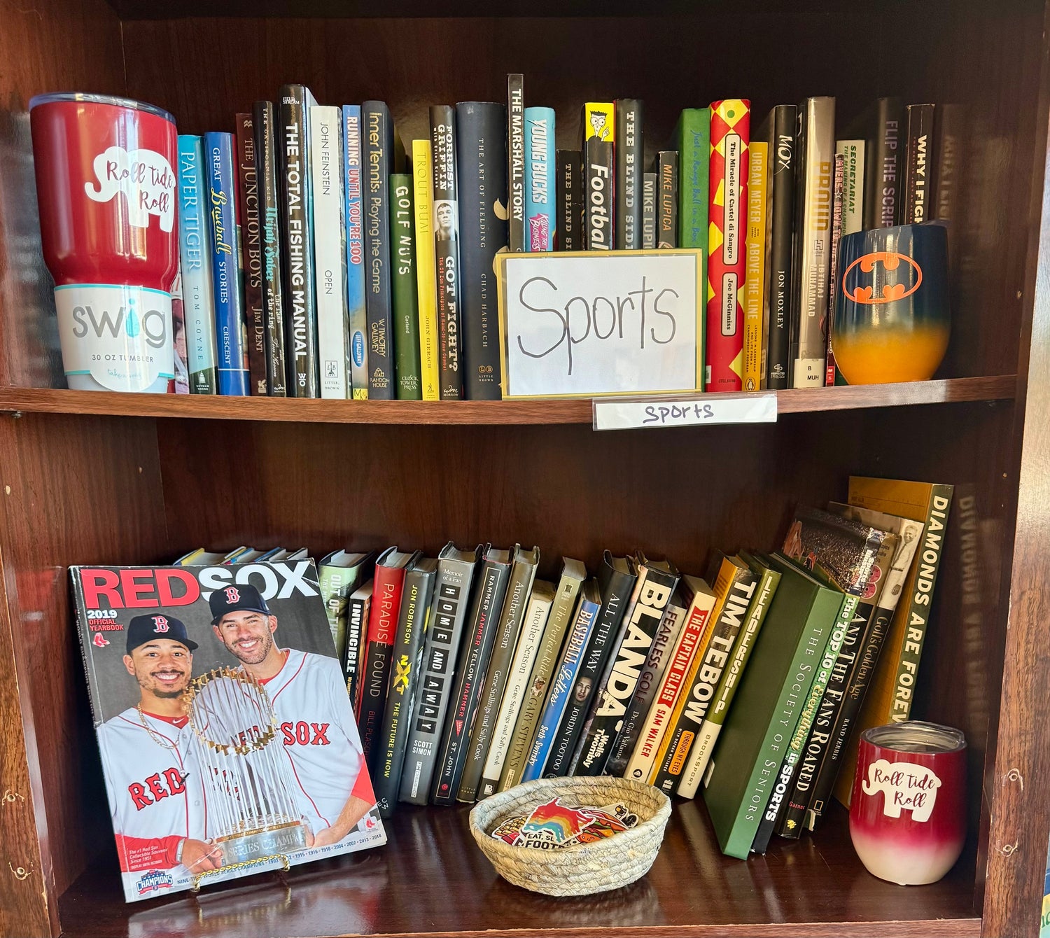 A dynamic bookstore display featuring sports fiction novels, a baseball glove, sneakers, and a coffee mug beside neatly stacked books, lit with natural light.