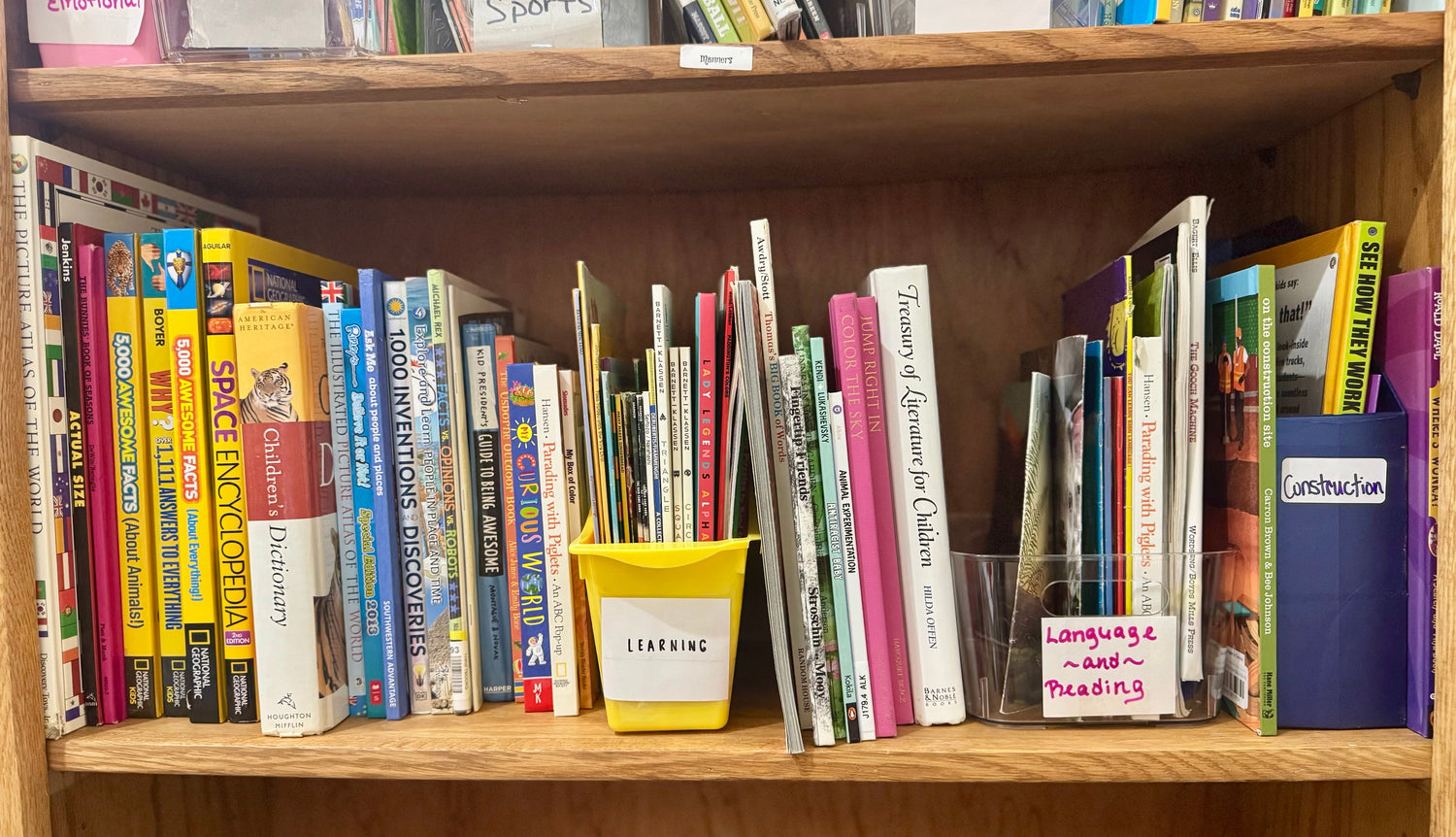A bright, cheerful bookstore display with early learning books for children arranged beside colorful alphabet blocks, counting toys, and playful classroom-style décor.