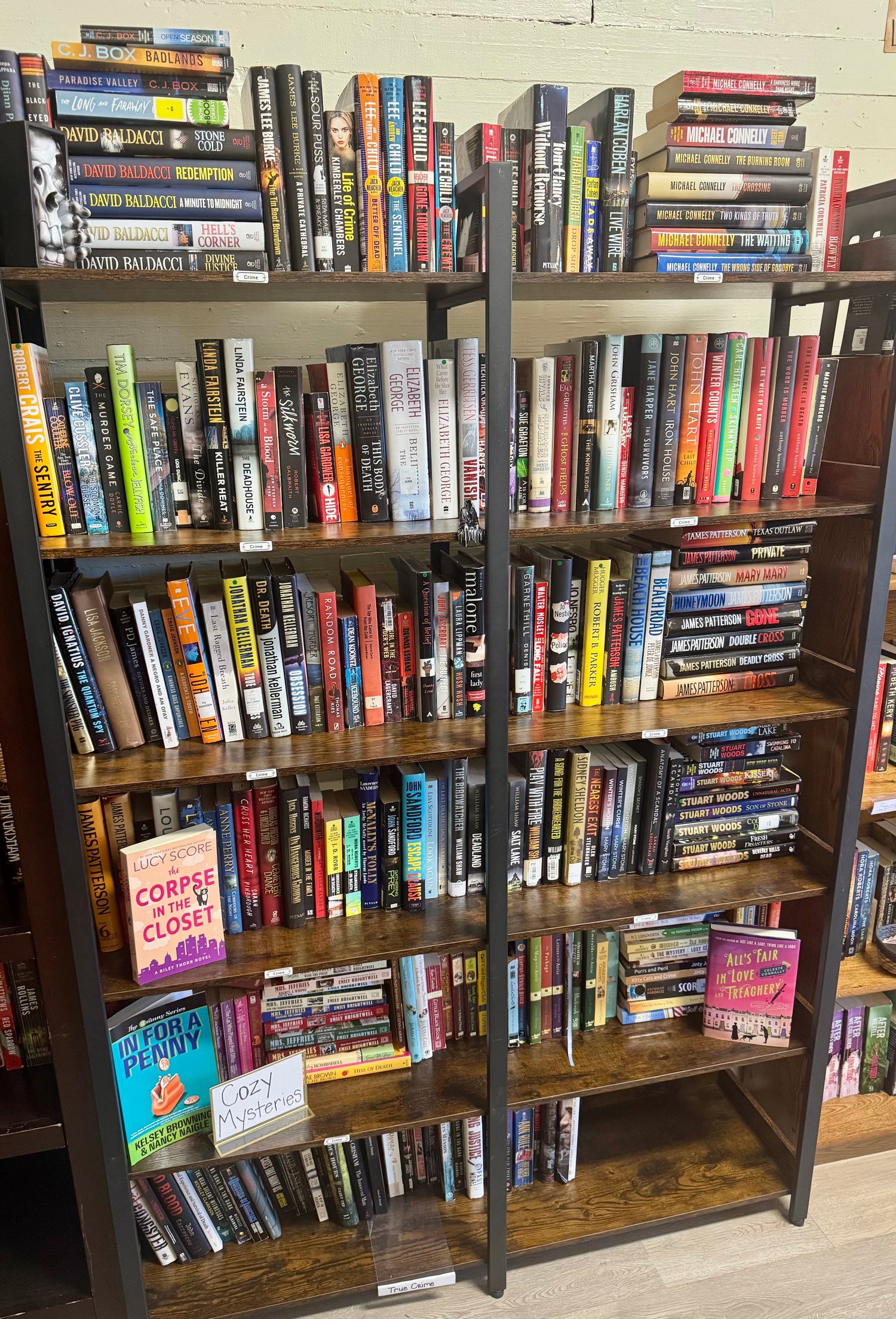 A dramatic bookstore display featuring crime and detective novels, a magnifying glass, scattered case notes, and low, moody lighting.