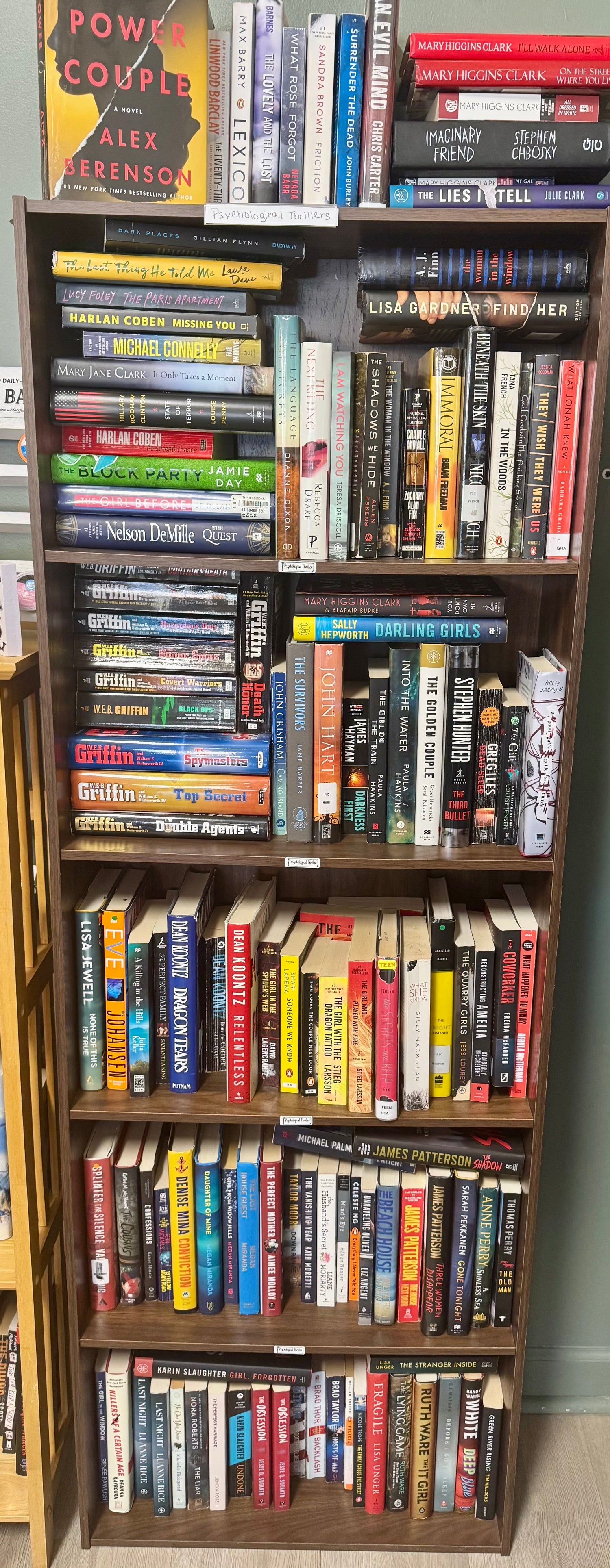 A dark and moody bookstore display featuring psychological thriller novels with intense cover art, dim lighting, and a coffee cup beside open books to suggest suspense and introspection.