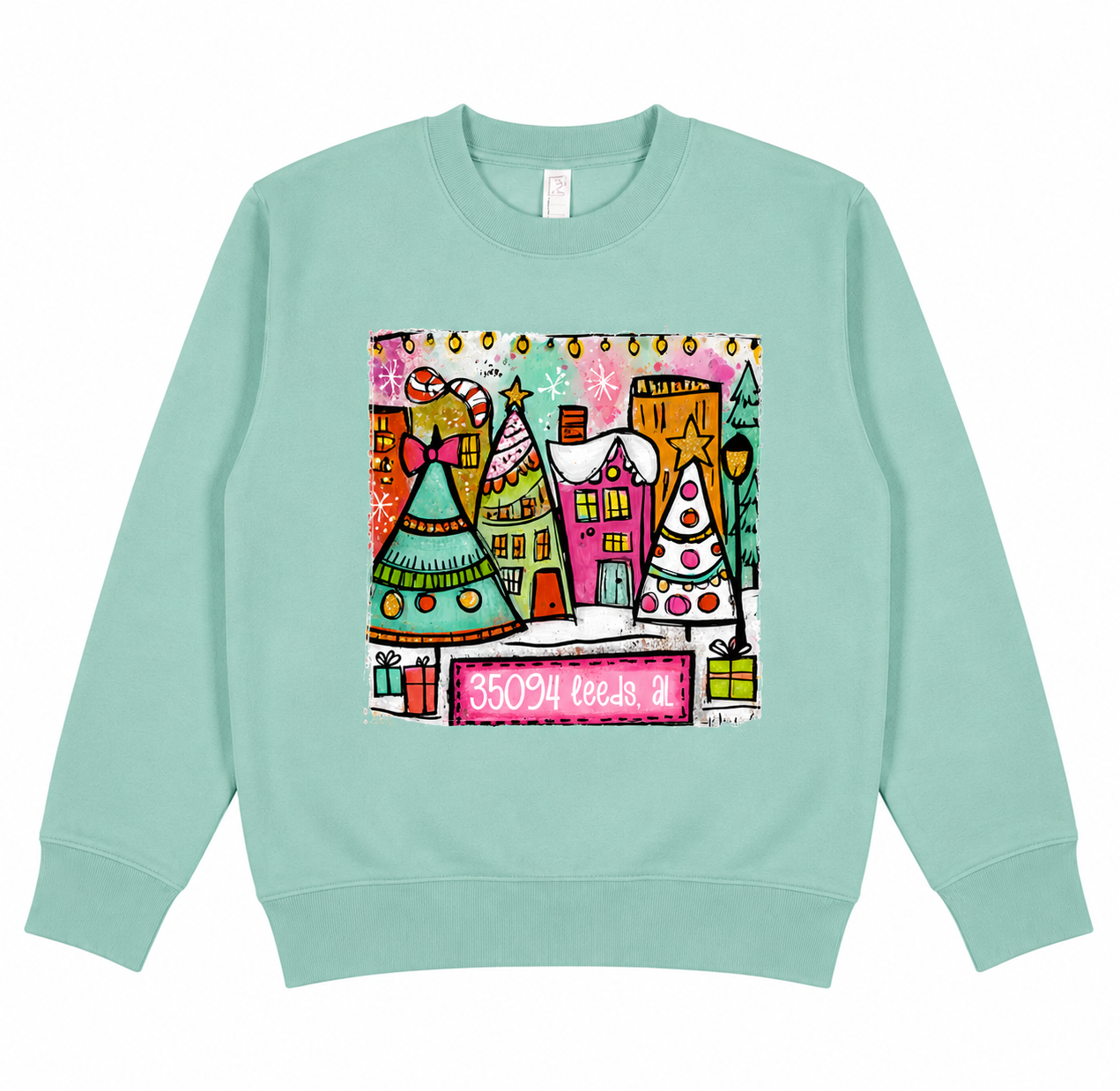 Colorful 35094 Leeds Alabama Christmas Village design featuring whimsical holiday houses, decorated Christmas trees, candy canes, presents, and festive winter artwork for short-sleeve shirts and crewneck sweatshirts.