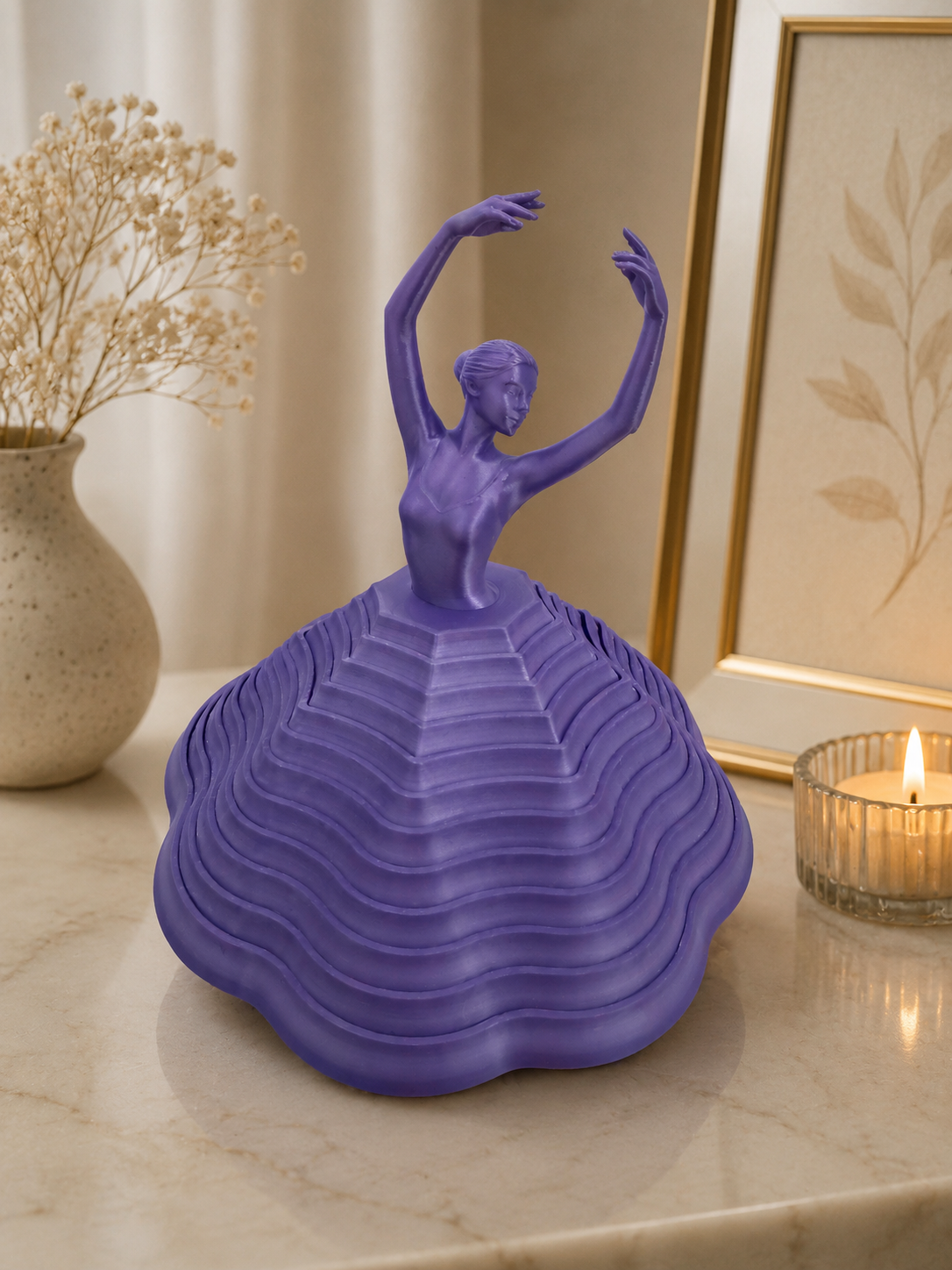 Purple dancer sculpture on a marble surface with a candle and vase in the background