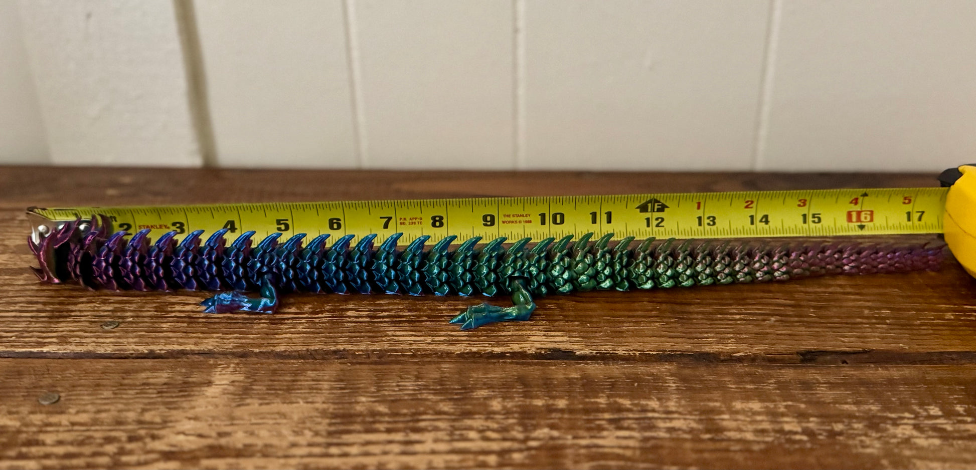 Colorful object on a wooden surface with a tape measure for scale.