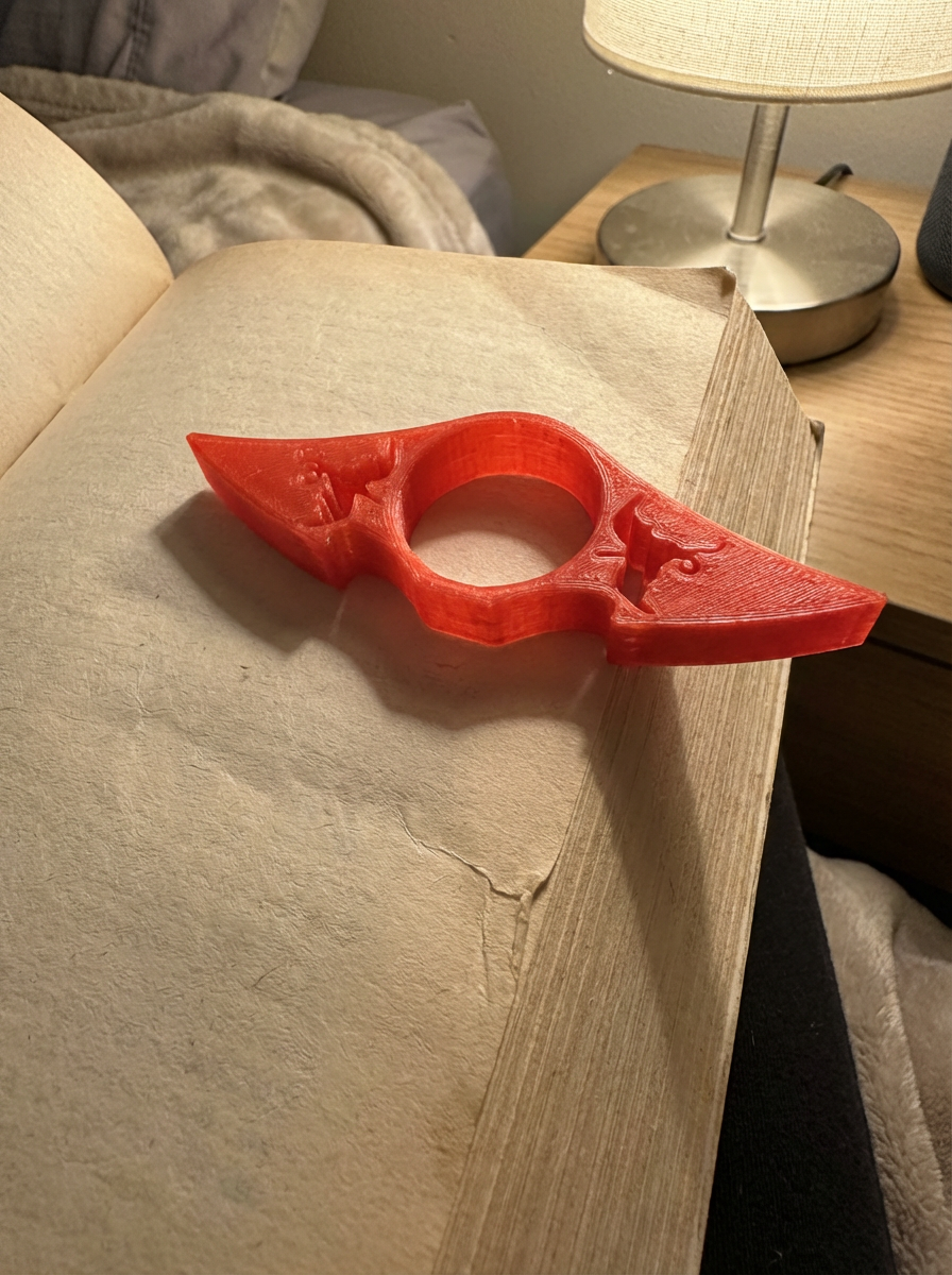 Red 3D printed thumb book holder holding pages open on an open book