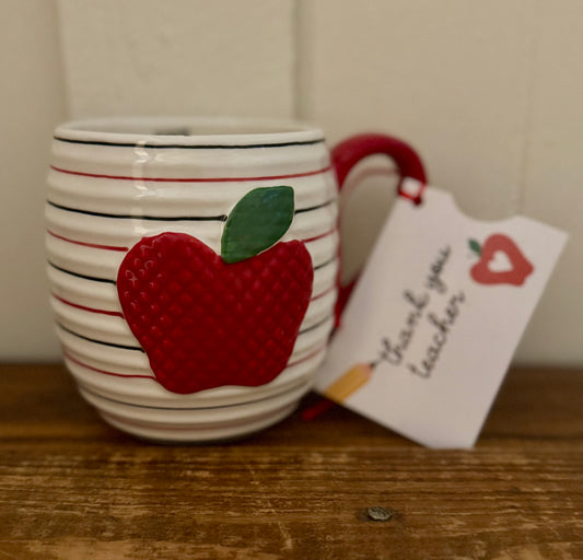 Mug with red apple design and 'Thank you teacher' tag on wooden surface