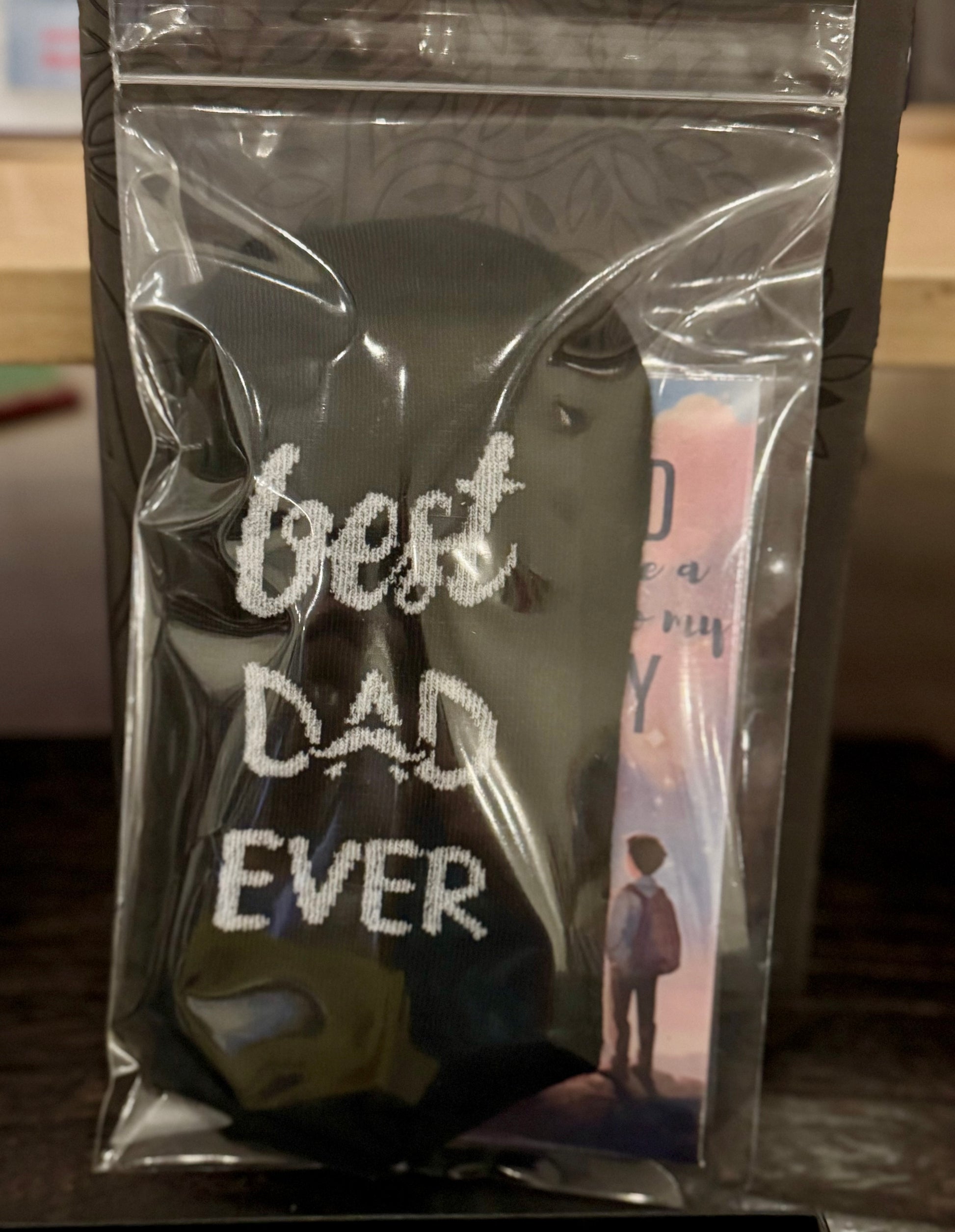 Pair of black socks that say Best Dad Ever, packaged with a free bookmark for Father's Day