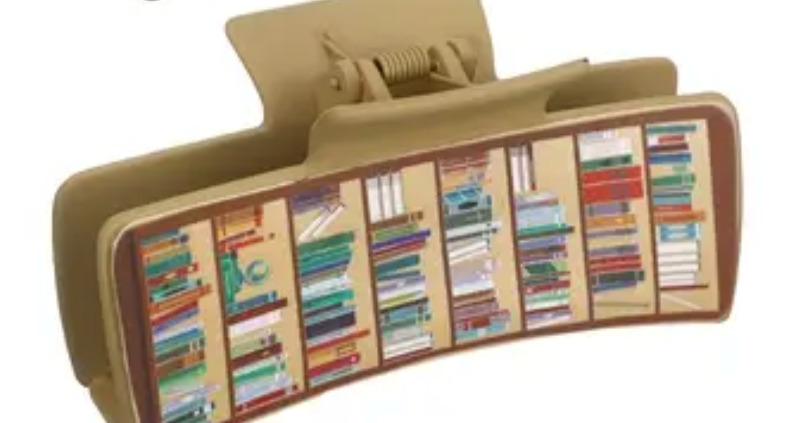 Book-shaped hair clip with colorful book spines on a beige background