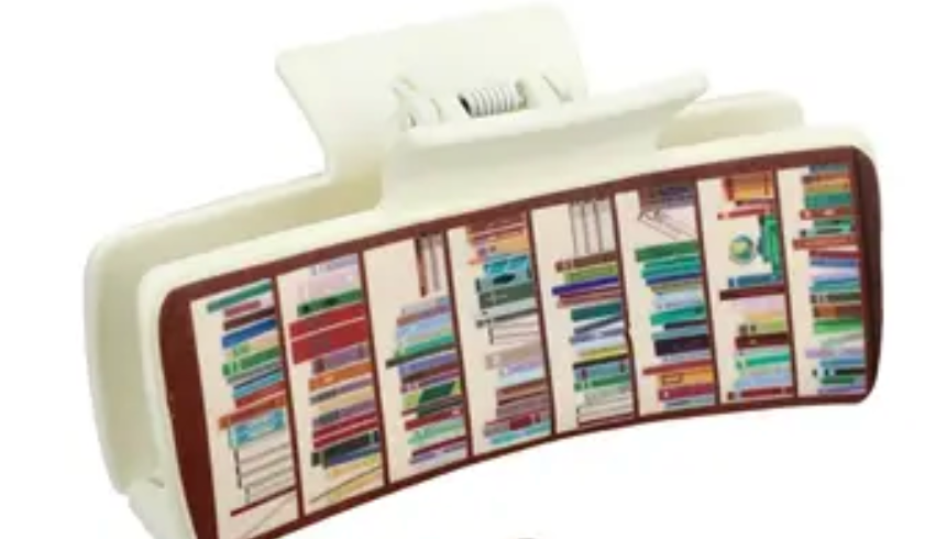 White hair clip with colorful book design on a white background