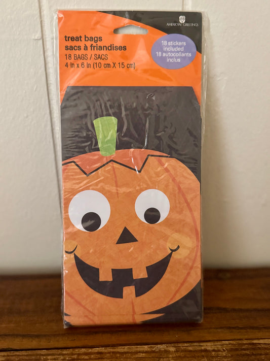 Pack of Halloween treat bags with a pumpkin design on a wooden surface.