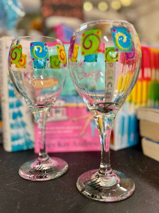 Pair of hand-painted wine glasses featuring colorful swirl square designs and signed glass bases