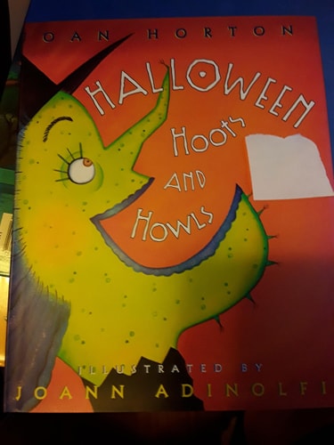 Book cover of 'Halloween Hoots and Howls' with a colorful illustration on a red background.