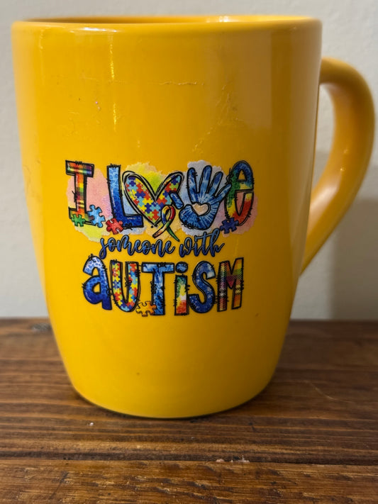 White ceramic mug with the phrase I Love Someone with Autism in bold, colorful lettering—ideal for showing support and love.