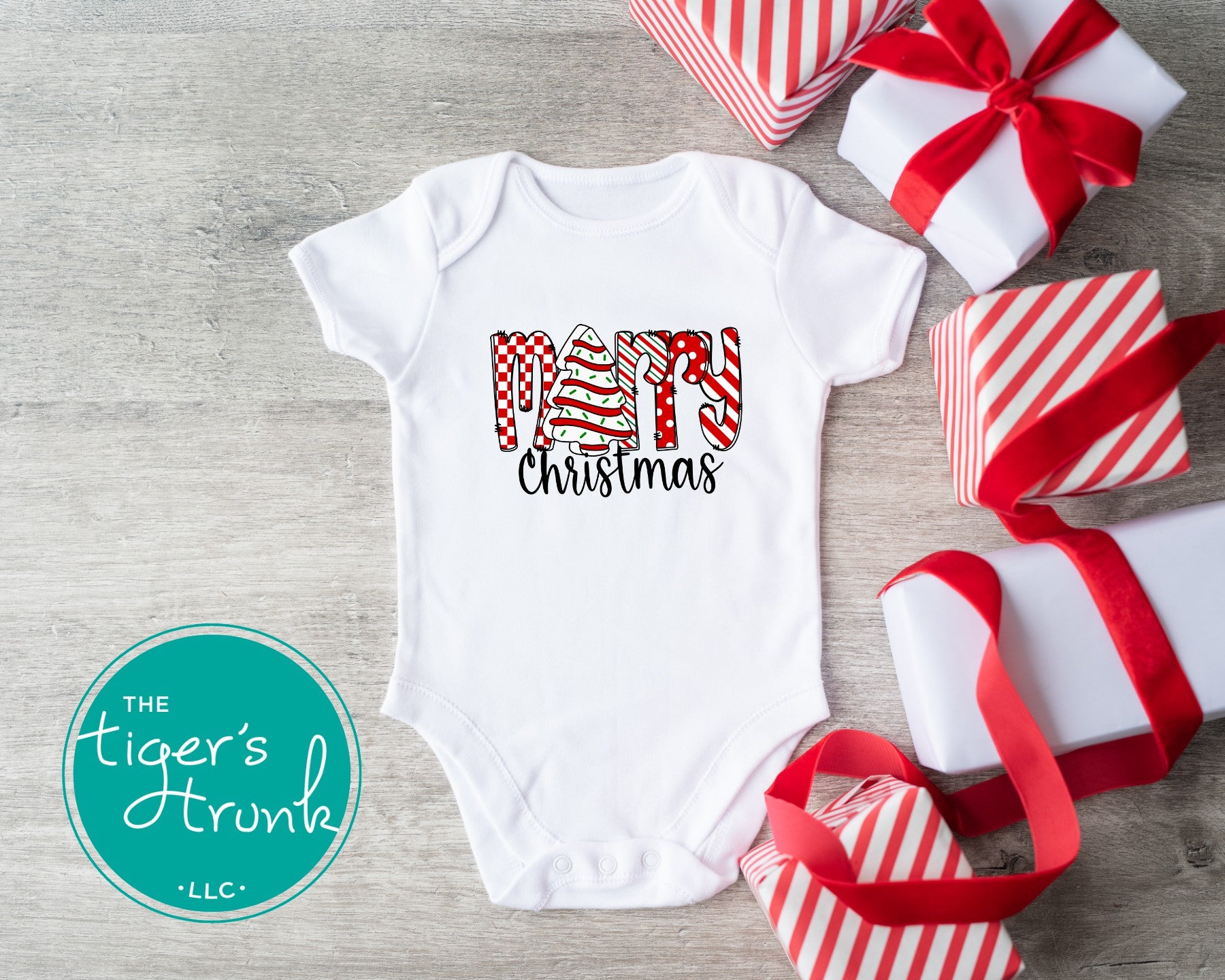 Baby bodysuit that says Merry Christmas with the letter E replaced by a Christmas tree snack cake design